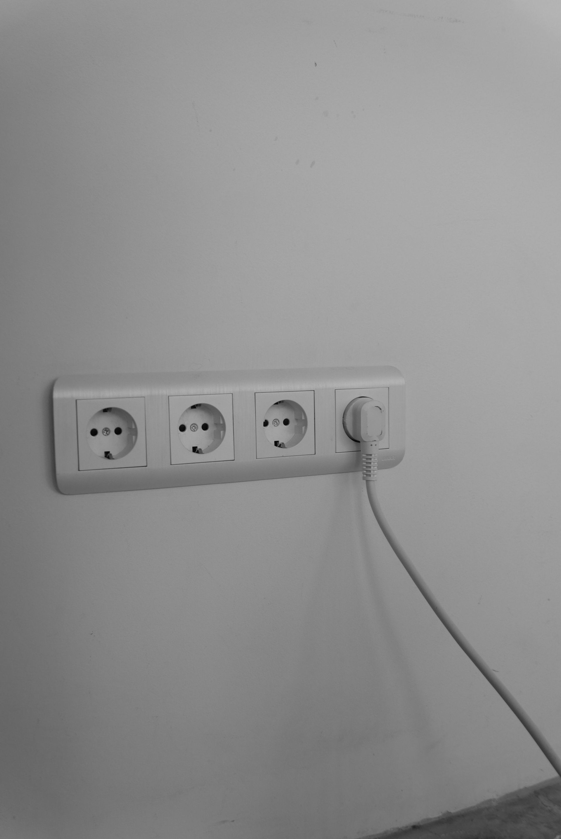 A clean and minimalist wall socket with a single plug connected, emphasizing modern interior design.